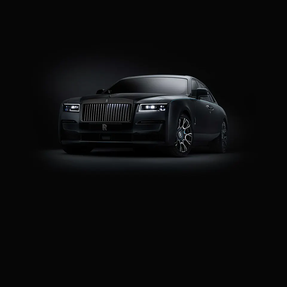 A blacked-out Rolls-Royce Ghost lit against a black studio background — the cinematic automotive art direction used across the site