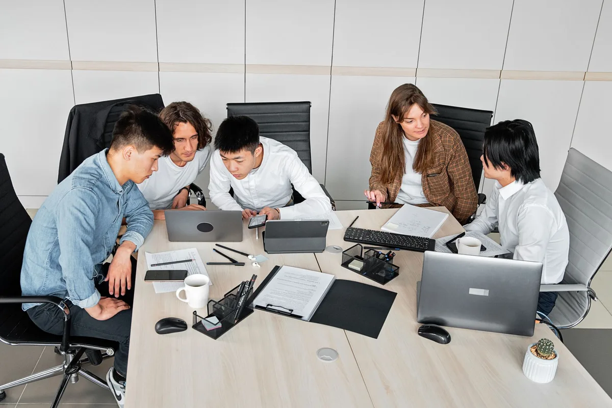 A web design team and client reviewing project scope together at a laptop - fixing scope before comparing quotes keeps prices honest