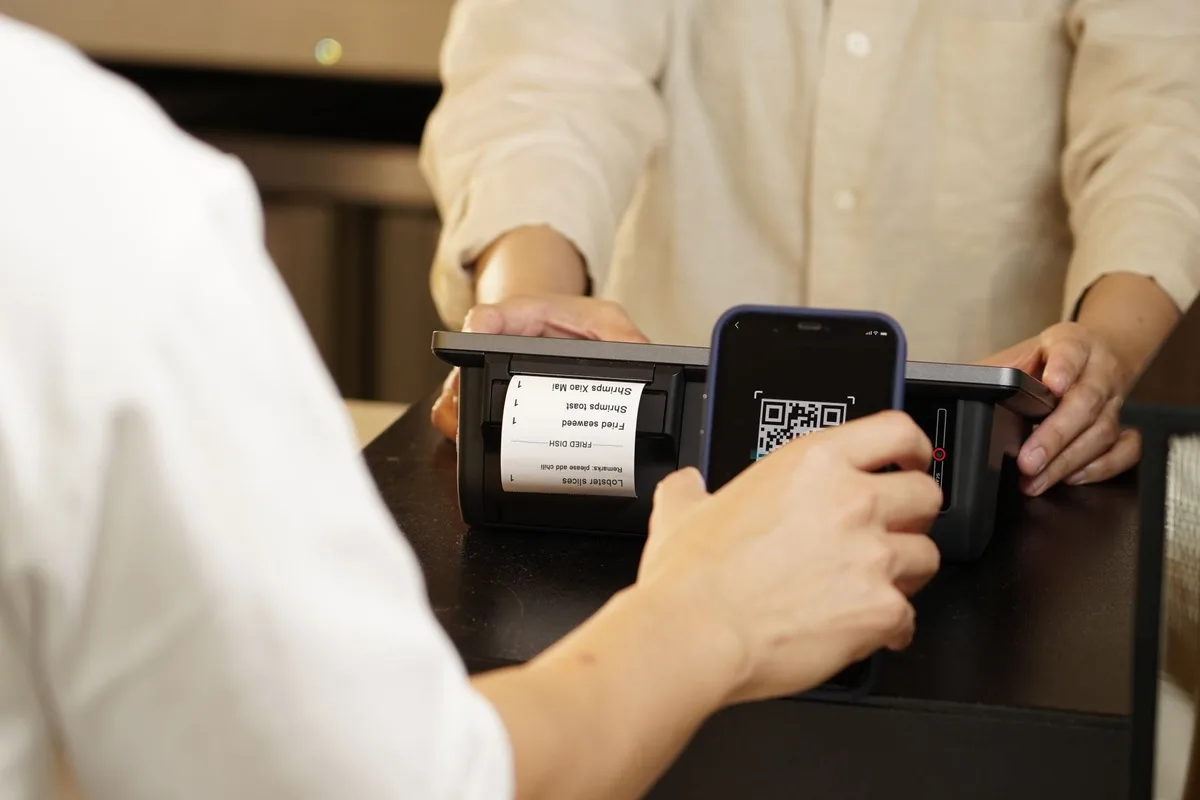 Customer scanning a shop QR code to pay by phone - the UPI-style payment flow Delhi e-commerce checkouts are built around
